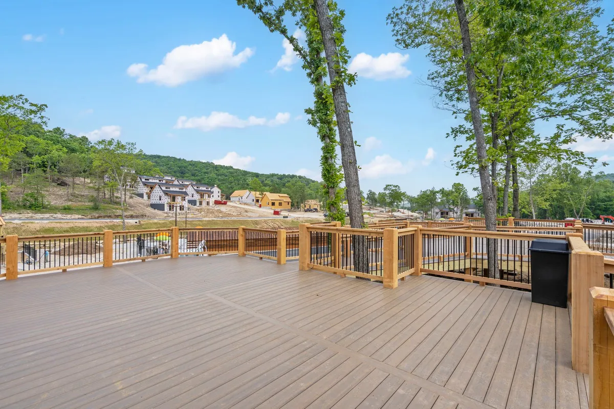 A newly built wooden deck stretches out, surrounded by tall trees and offering sweeping mountain views. The inviting outdoor space is perfect for gatherings, relaxing after a day of adventure, or simply soaking in the tranquility of nature. The deck is suited for lounging, hosting a barbecue, or enjoying the sunset with friends or family.